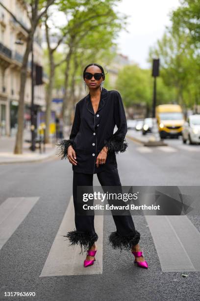 Emilie Joseph @in_fashionwetrust wears silver rhinestones Isabel Marant earrings, black sunglasses, a black ribbed buttoned long shirt with black...