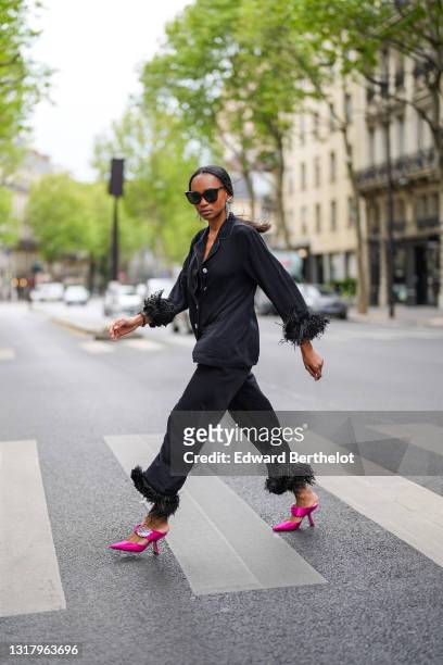 Emilie Joseph @in_fashionwetrust wears silver rhinestones Isabel Marant earrings, black sunglasses, a black ribbed buttoned long shirt with black...