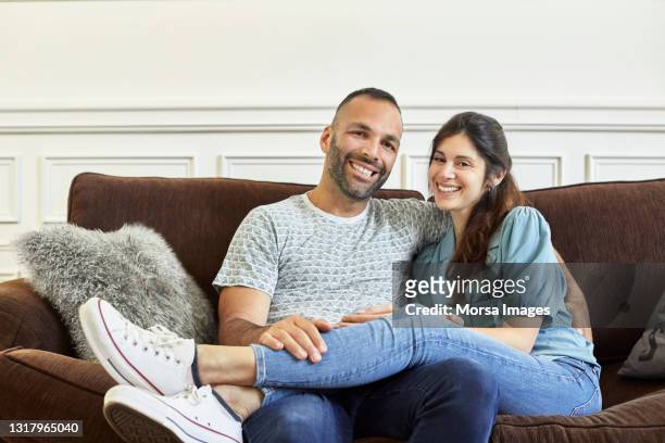 portrait of happy mid adult couple sitting at home - familie sofa stock pictures, royalty-free photos & images