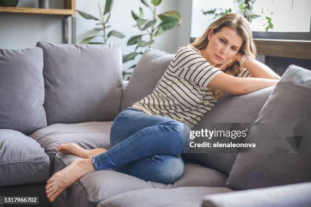 attractive middle aged woman sitting on the couch (negative emotions) - shock stock pictures, royalty-free photos & images