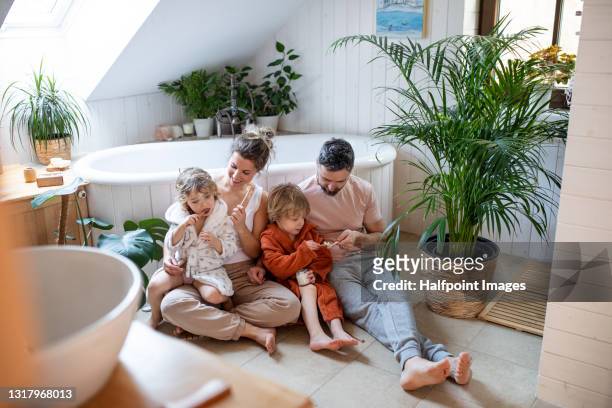 family with small children in bathroom at home, using bamboo toothbrushes. - badkamer huis stockfoto's en -beelden
