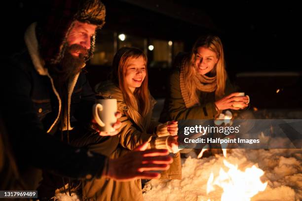 parents with small daughter on holiday in snowy winter nature, marshmallows on barbecue. - family in snow mountain stock-fotos und bilder