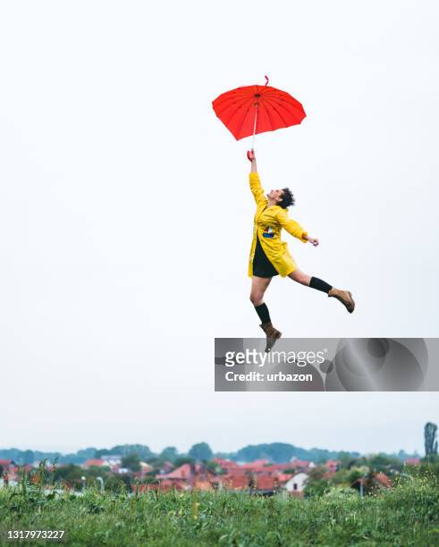 woman flying of the ground hanging on umbrella - hesitant to dance stock pictures, royalty-free photos & images