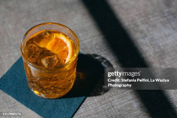 drinking glass of crodino/aperol/spritz on a table. - glass shadow stockfoto's en -beelden