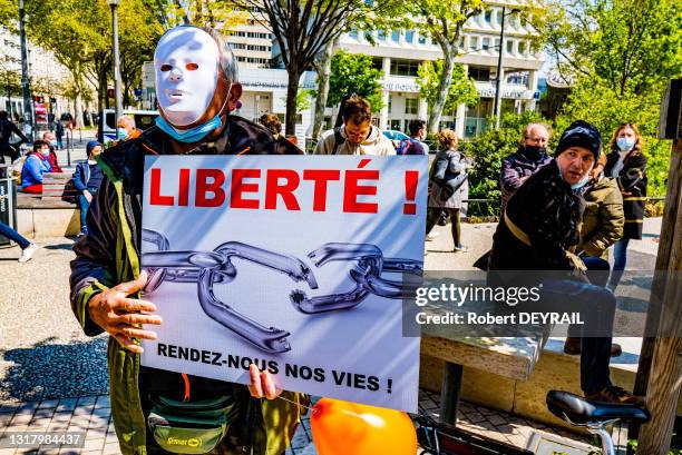 Un militant masqué porte une pancarte "LIBERTÉ ! RENDEZ NOUS NOS VIES" lors du rassemblement "anti-confinement" contre les masques, pour la...