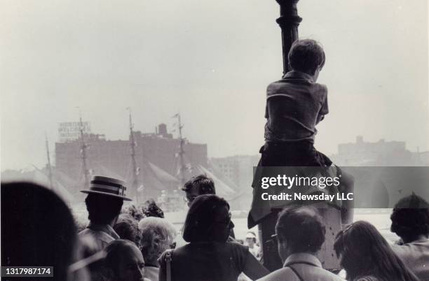 Boy sits atop a pole at 33rd St. And the West Side Drive in Manhattan to get a good look at the ships passing by during OpSail, July 4, 1976.