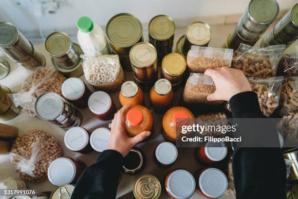 a mulher está reorganizando a comida não periável no banco de alimentos. - lata recipiente - fotografias e filmes do acervo