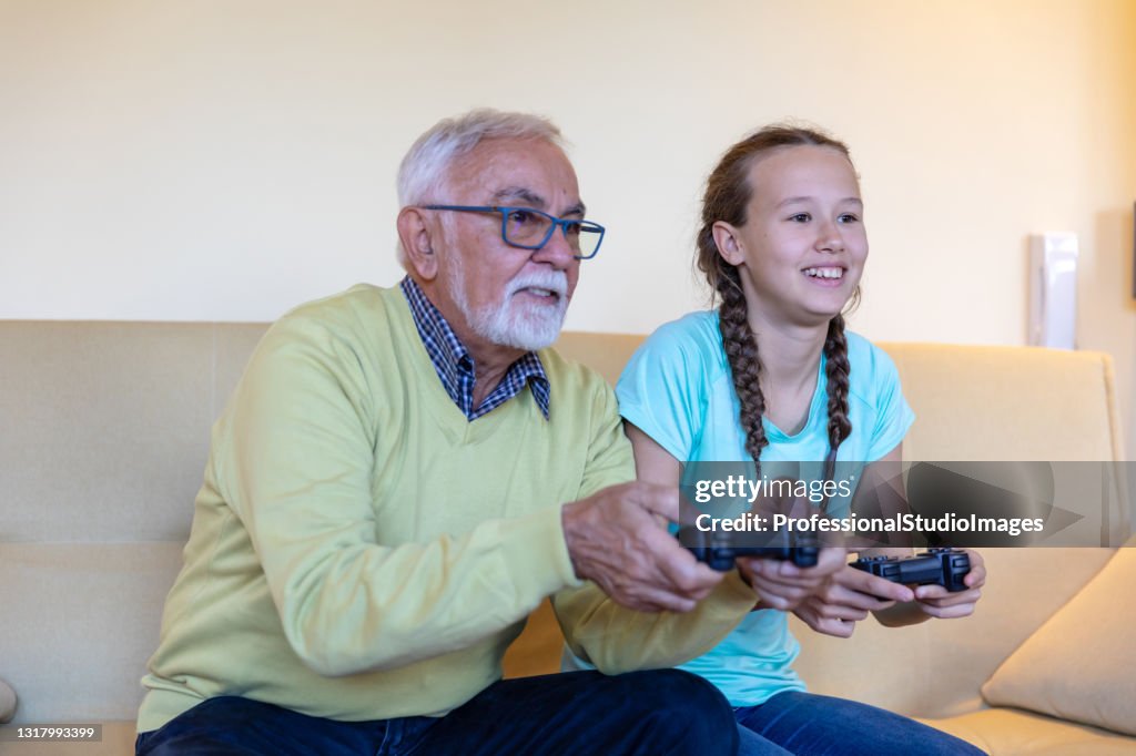 A Garota Sorridente e seu avô estão jogando videogame juntos em casa.