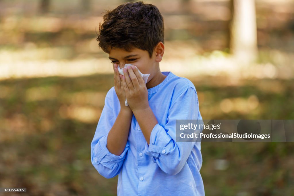 Boy With Seasonal Flu is Walking in Park and Coughing in Paper Tissues.