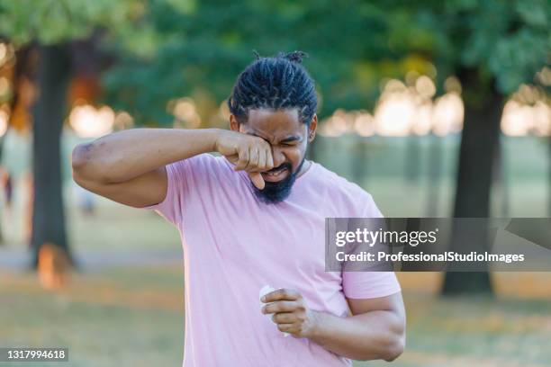 un hombre afroamericano está teniendo problemas de alergia fuera de la naturaleza. - dry fotografías e imágenes de stock