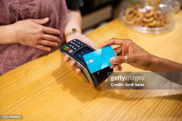woman's hand paying with a blue credit card - credit card stock pictures, royalty-free photos & images