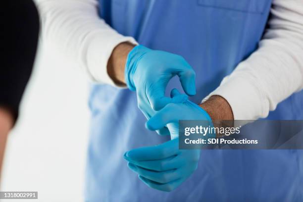 unrecognizable doctor puts on protective gloves before work - luva preta imagens e fotografias de stock