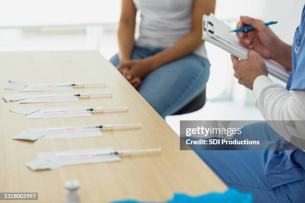 in der impfklinik stellt die krankenschwester weibliche patientenfragen - vaccination center stock-fotos und bilder