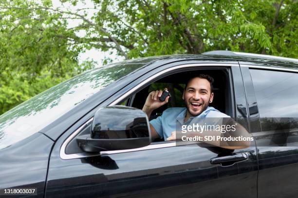 man holds up keys and smiles after online car purchase - car owner stock pictures, royalty-free photos & images