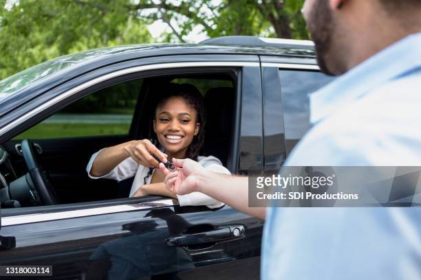de medio volwassen vrouw glimlacht terwijl het overhandigen van sleutels aan valet - valet stockfoto's en -beelden