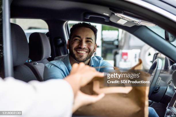 l'uomo sorride mentre raccoglie l'ordine sul marciapiede - fast food restaurant foto e immagini stock