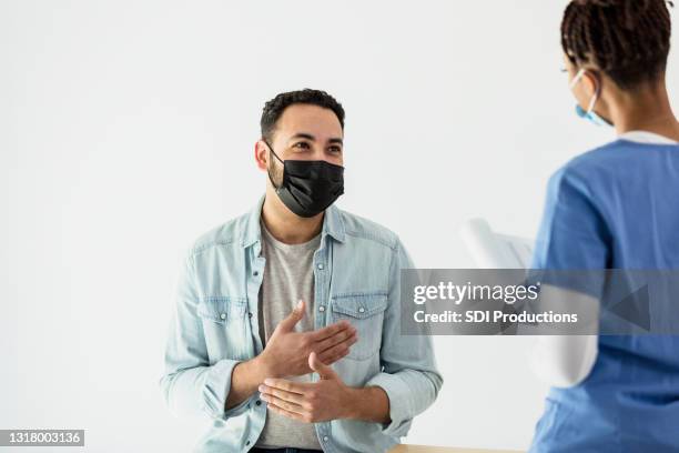 mid adult patient answers questions about health - mask man stock pictures, royalty-free photos & images