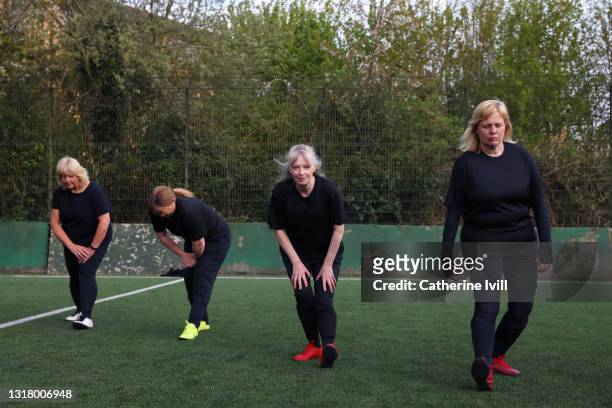 female soccer players warming up and stretching on soccer pitch - menopossibilities stock-fotos und bilder