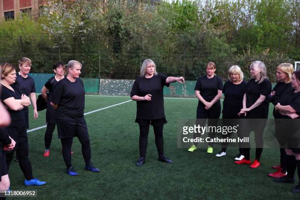 female soccer coach discussing strategy with women's soccer team on soccer pitch - menopossibilities stock-fotos und bilder