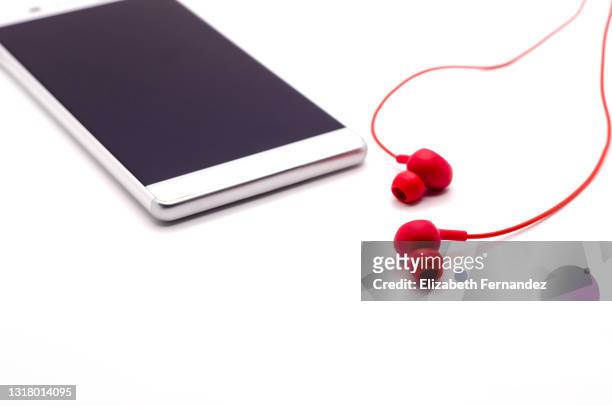 red headphones and smartphone on a white background - personal stereo stockfoto's en -beelden