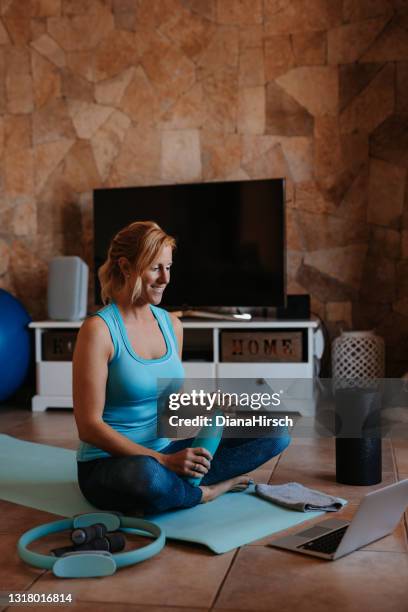 beautiful blonde smiling woman with a water bottle during her sport exercises at home - home fitness stock pictures, royalty-free photos & images