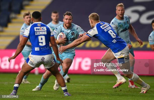 Matty Ashurst of Wakefield is tackled by Kruise Leeming and Mikolaj Oledzki of Leeds during the Betfred Super League match between Leeds Rhinos and...