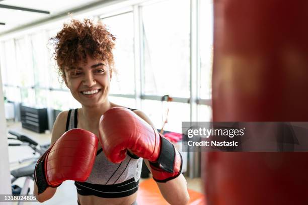 giovane donna sorridente che calcia in palestra - kick boxing foto e immagini stock