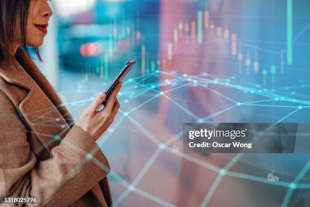 woman analysing and checking stock market over smartphone in downtown financial district - cryptocurrency trading stock pictures, royalty-free photos & images