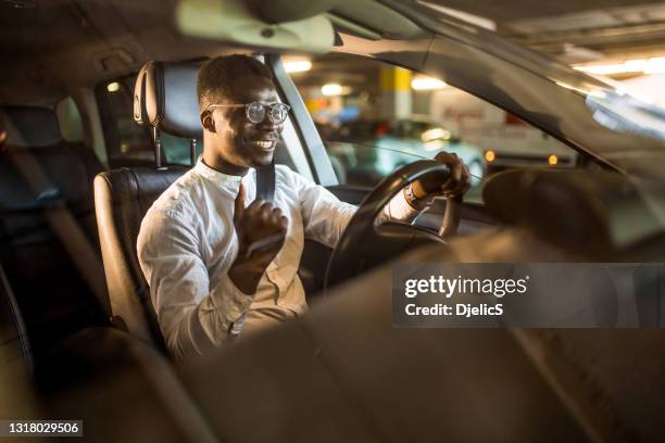 gelukkige afrikaanse amerikaanse zakenman die aan muziek luistert terwijl het drijven van zijn auto. - business person driving stockfoto's en -beelden