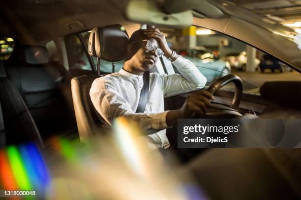 uitgeputte afrikaanse amerikaanse zakenman die een auto drijft. - sad commuter stockfoto's en -beelden