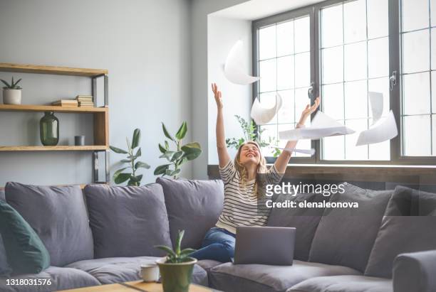 attractive middle aged woman sitting on the couch( laptop, paperwork, throwing) - throwing stock pictures, royalty-free photos & images