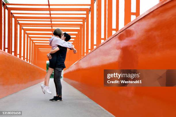 teenage couple kissing on orange bridge - boy girl kissing stock pictures, royalty-free photos & images