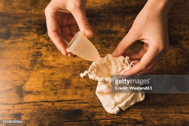 woman inserting menstrual cup in cloth bag on table - menstrual cup stock pictures, royalty-free photos & images