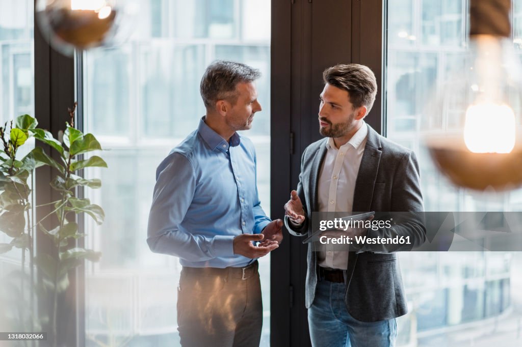 Male professionals discussing over digital tablet in office