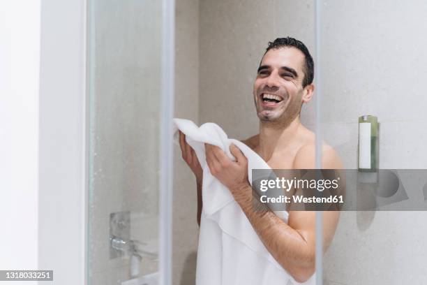 cheerful man drying off with towel after having bath - bath towels stock-fotos und bilder