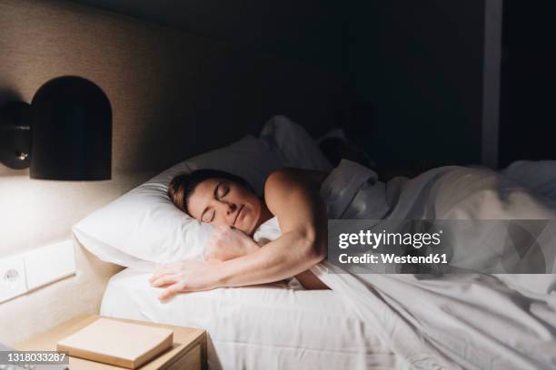 beautiful woman sleeping on bed in hotel room - women sleeping stockfoto's en -beelden