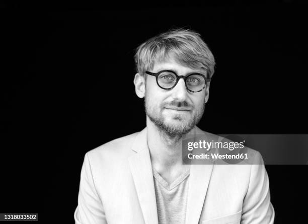 man wearing eyeglasses in front of black background - portrait professional dark background stock-fotos und bilder