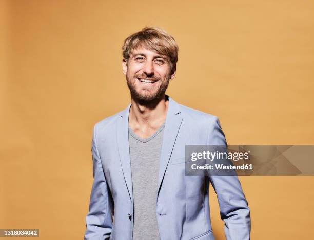 happy man standing in front of yellow wall - veste homme photos et images de collection