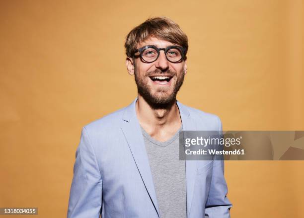 man wearing eyeglasses laughing in front of yellow wall - mid adult stock-fotos und bilder