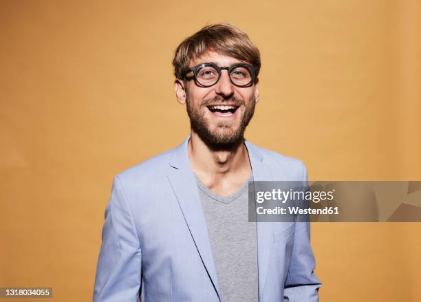 man wearing eyeglasses laughing in front of yellow wall - portraits laugh ストックフォトと画像