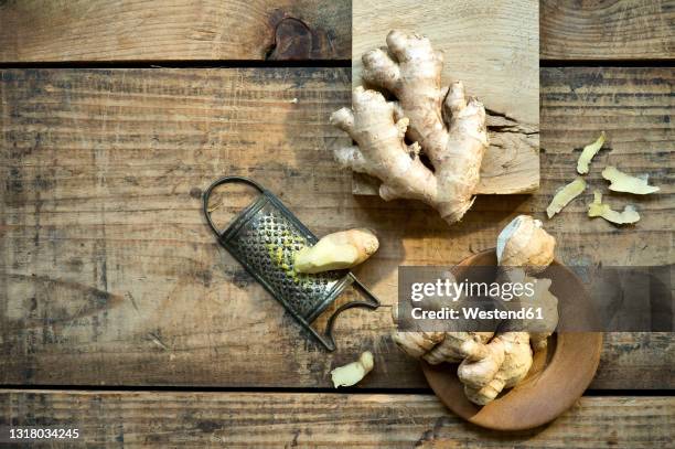 ginger roots and old grater lying on wooden surface - ショウガ ストックフォトと画像