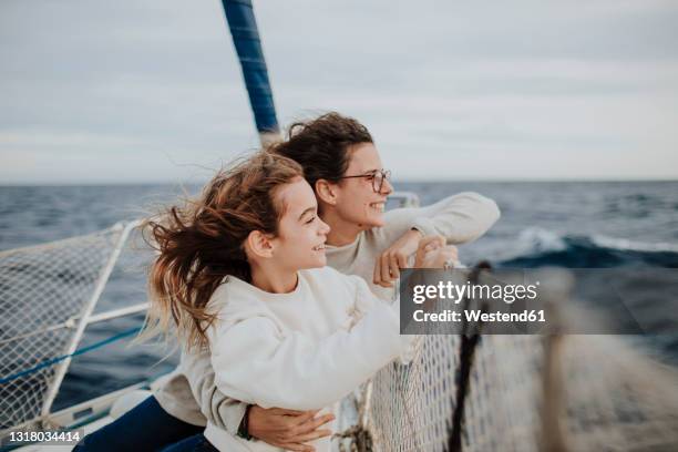 mother and daughter looking at view while traveling on sailboat during vacation - mother and daughter in the wind stock-fotos und bilder