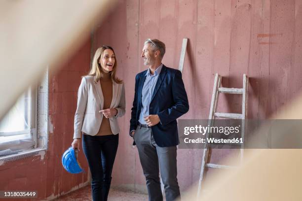 smiling female colleague discussing with male architect at construction site - foundations conversations with suits stock-fotos und bilder