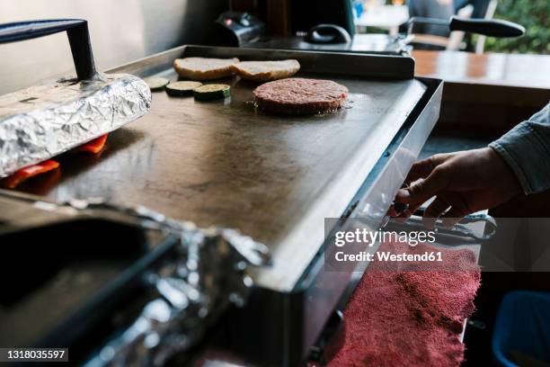 burger patty on griddle at restaurant - burger grill stockfoto's en -beelden