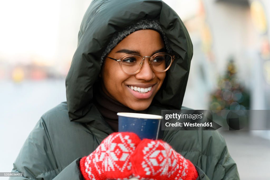 Smiling woman with reusable cup wearing gloves in winter