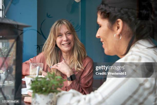 happy woman looking at female friend at cafeteria - female with friend in coffee stock pictures, royalty-free photos & images