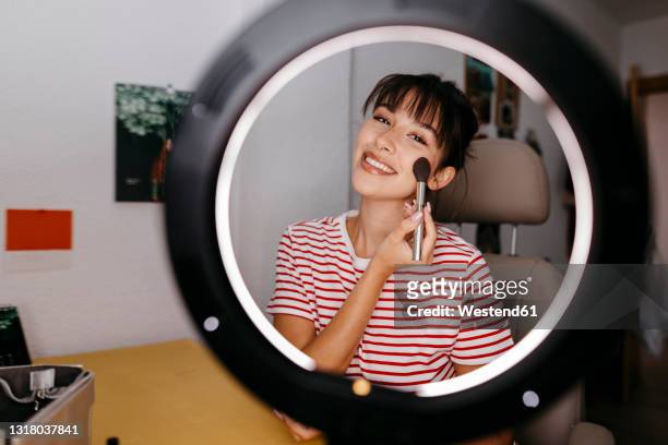 beautiful female influencer applying blusher at studio - make up blush imagens e fotografias de stock