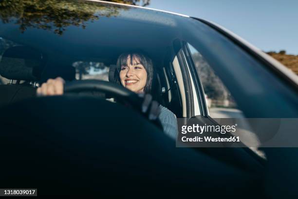 young woman driving car seen through windshield - voiture conducteur photos et images de collection