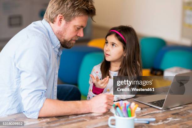girl gesturing while talking with father during e-learning at table - e girls stock pictures, royalty-free photos & images