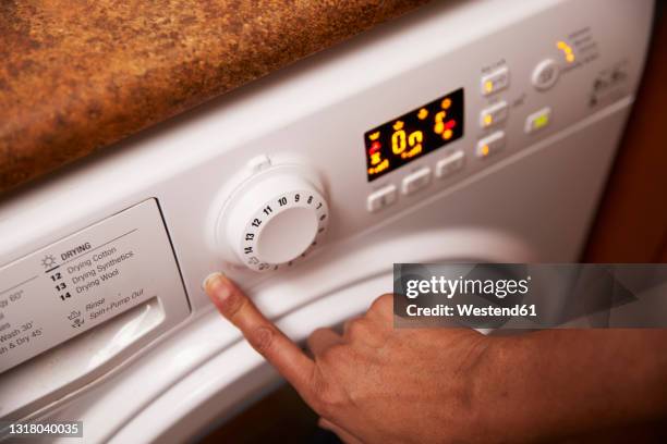 woman operating washing machine at home - washing machine stock pictures, royalty-free photos & images